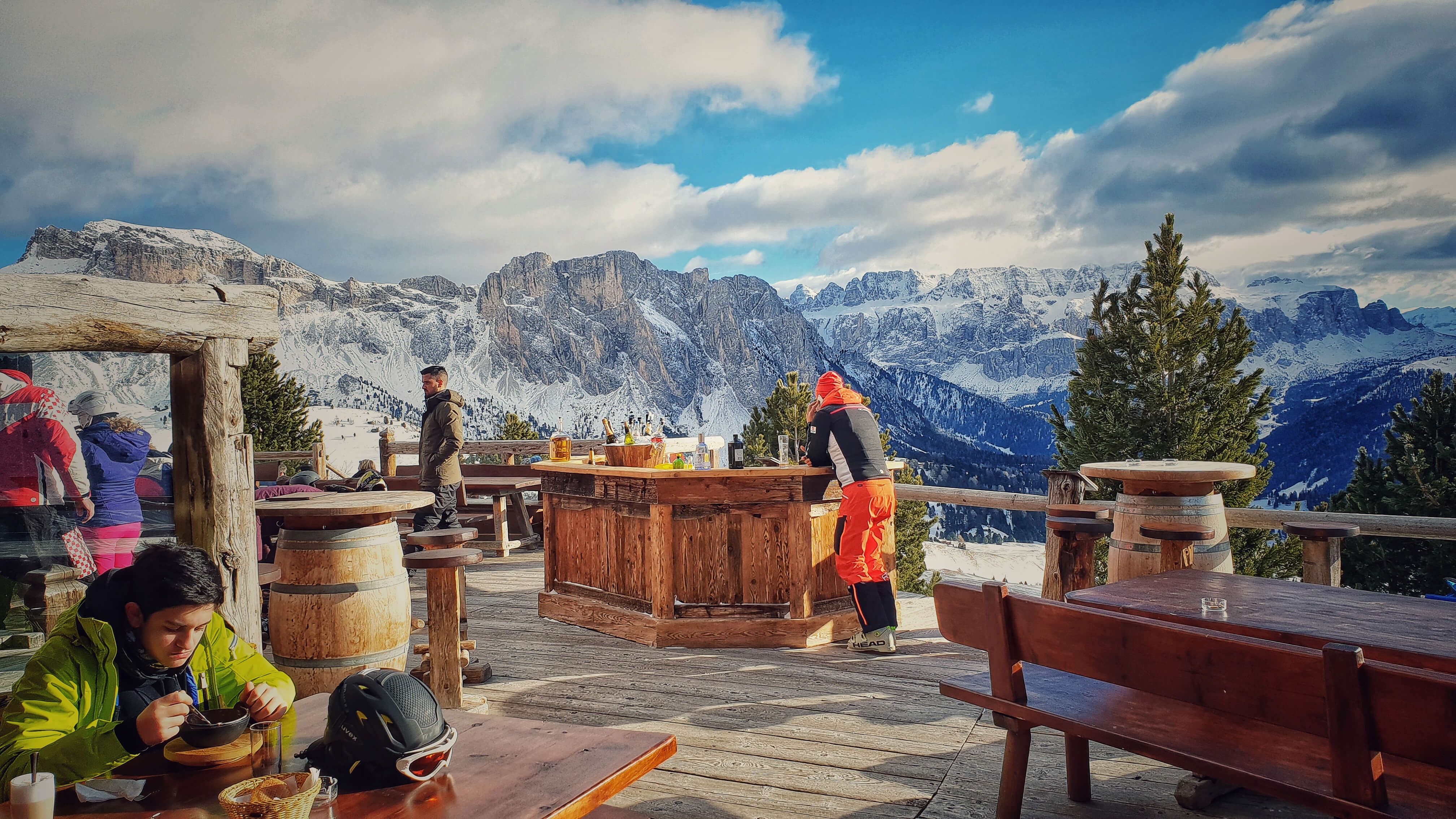 man relaxing at the bar of restaurant with stunning dolomites scenery behind him