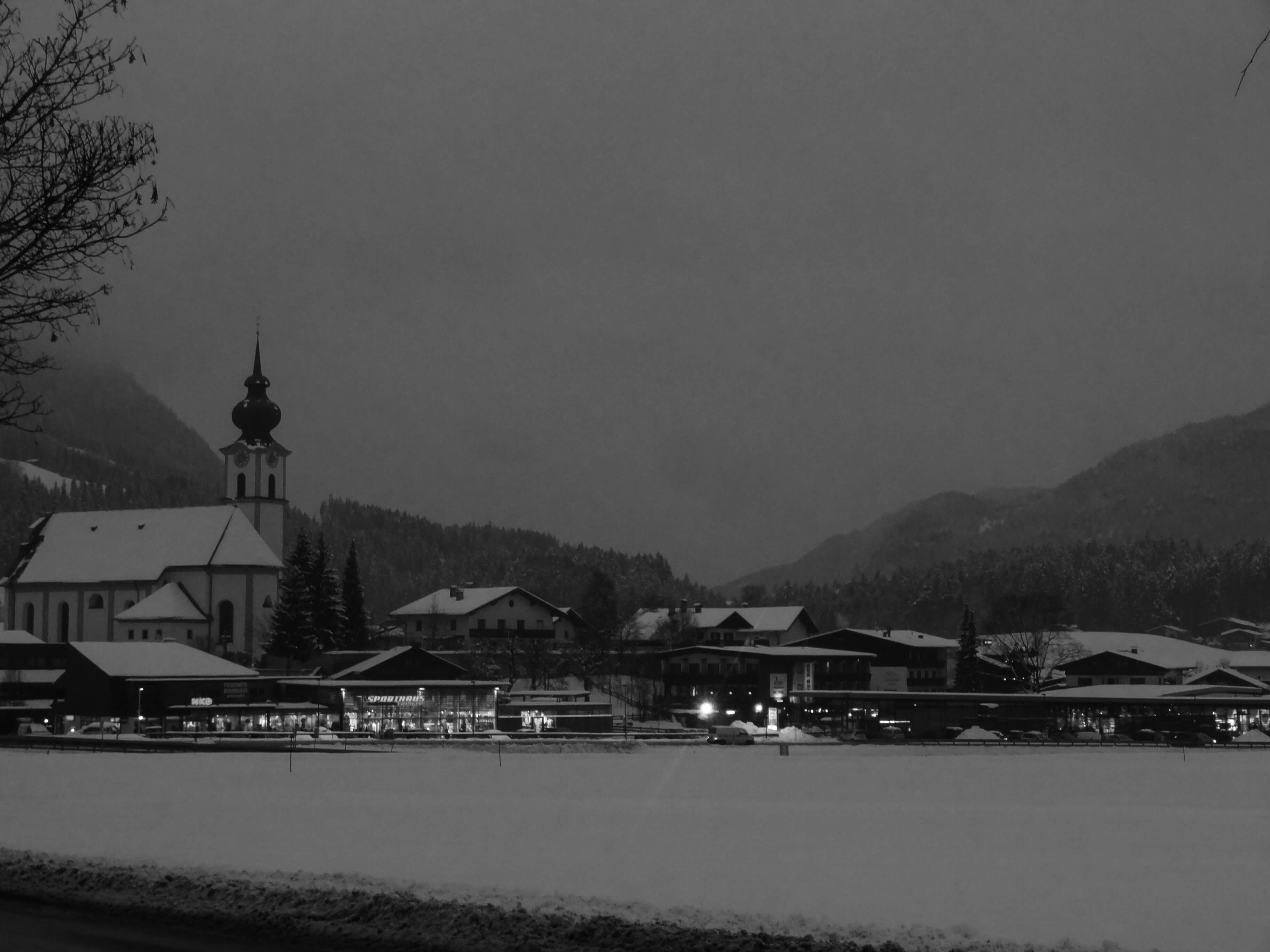 looking across to the church and houses in soll austria in the winter with snow and lights twinkling at twilight