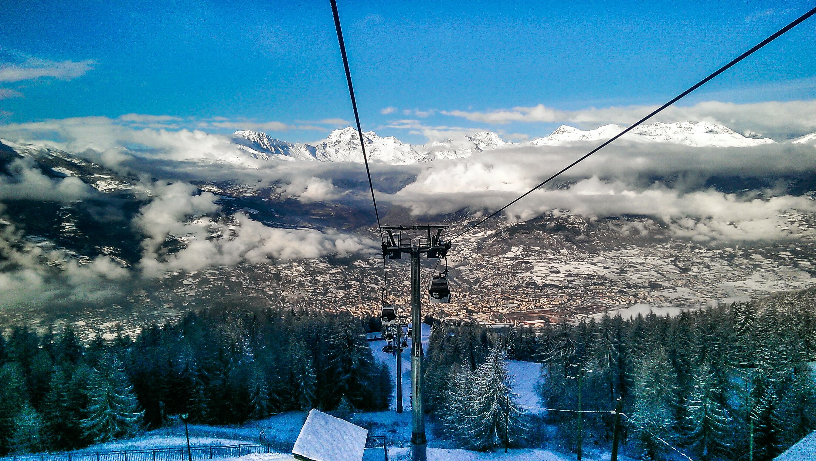 looking across the aosta valley from the top gondola station in Pila clouds rolling in and green fir trees in the valley