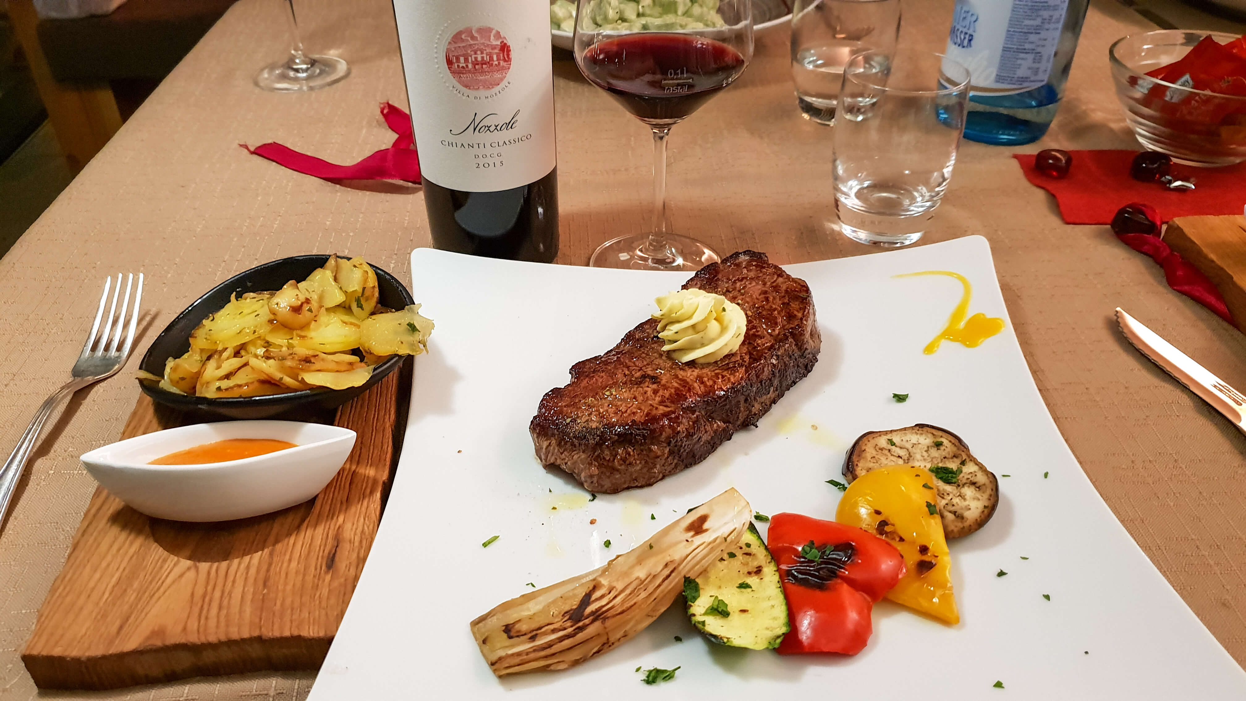 medium-steak-with-potatoes-and-mountain-vegetables-served-with-a-bottle-of-red-chianti-wine-in-selva-di-val-gardena-italy