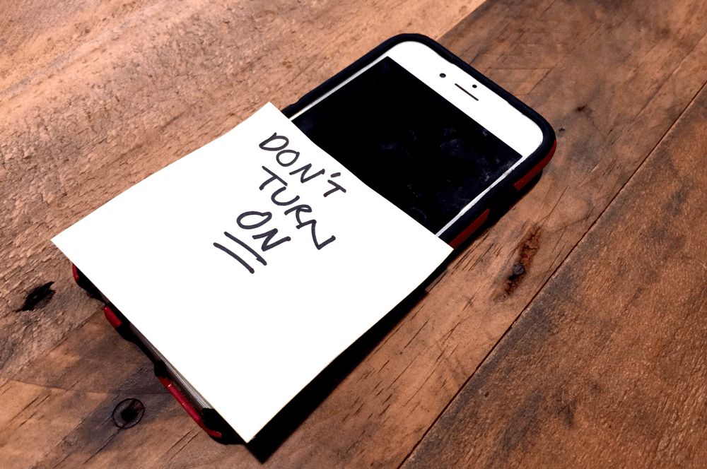 iphone with a white post it note saying don't turn on for smartphone detox