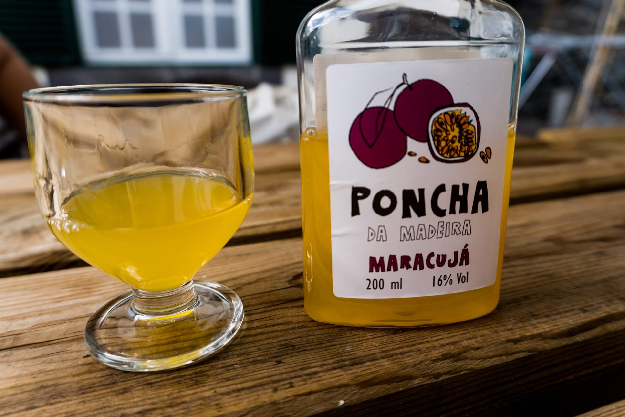 glass of poncha and accompanying bottle in passion fruit flavour sitting on a table
