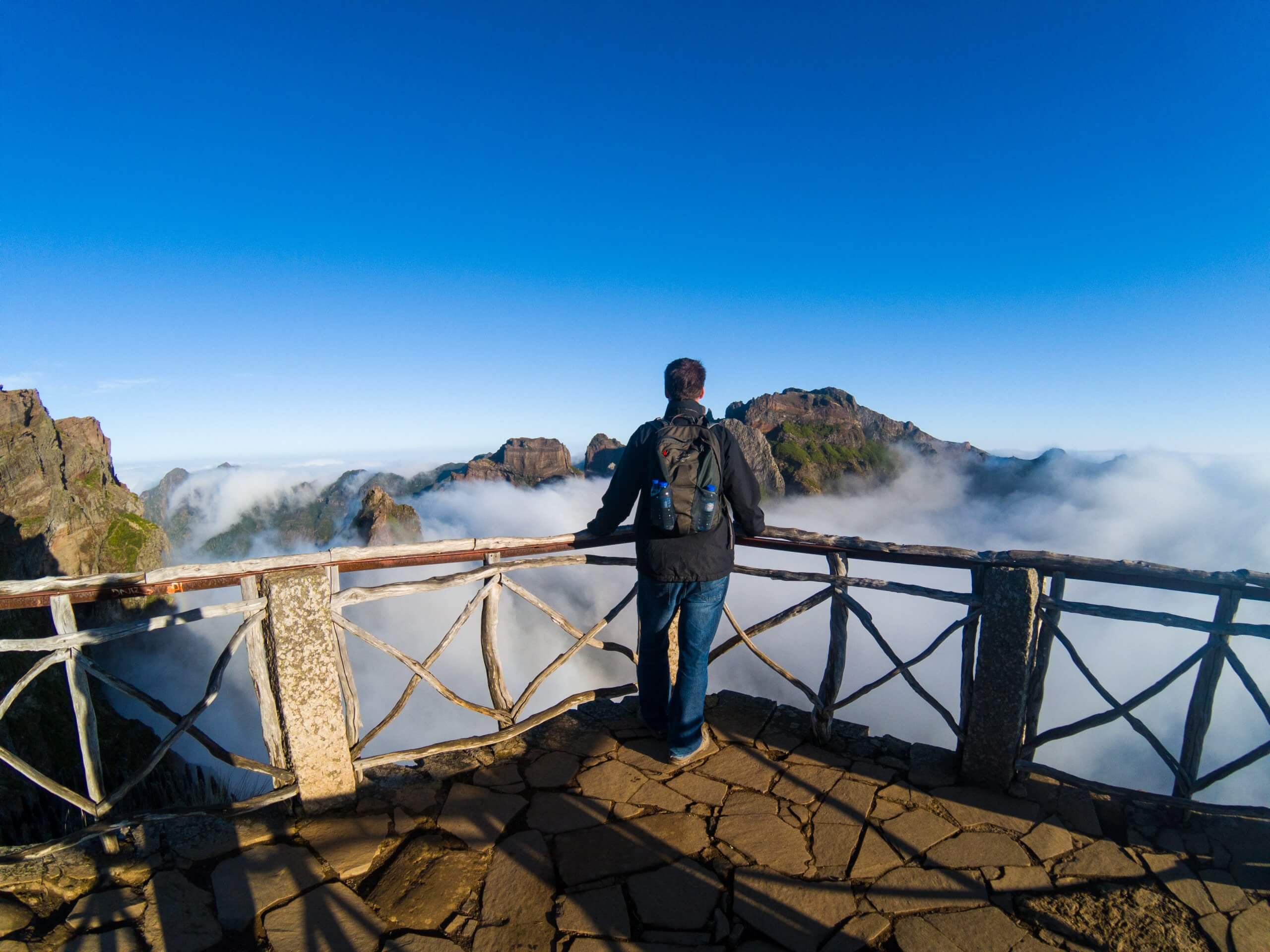 dave with back to camera standing at viewpoint overlooking some of the highest mountains of madeira