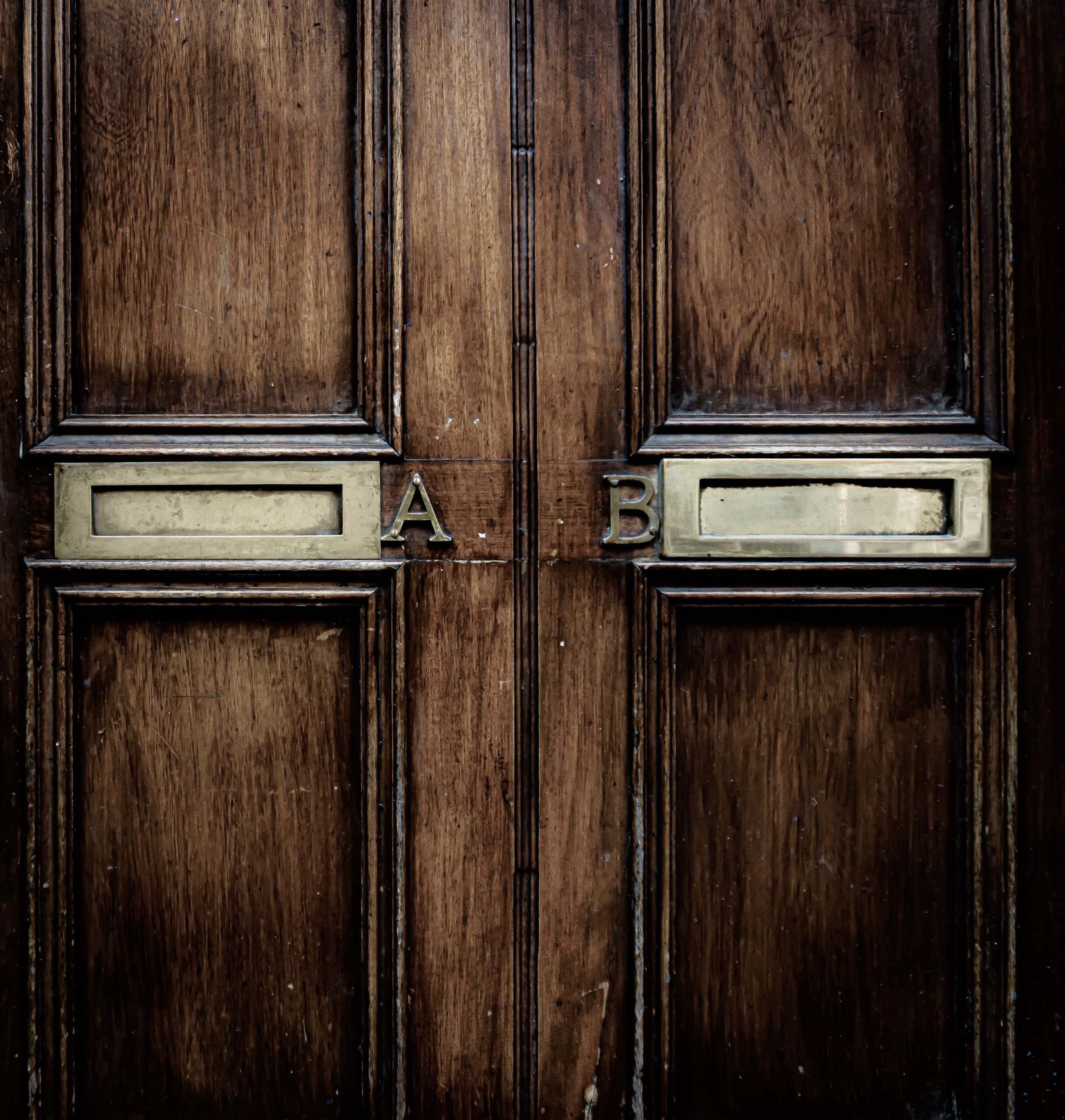 brown wooden door with two identical letterboxes labelled A and B